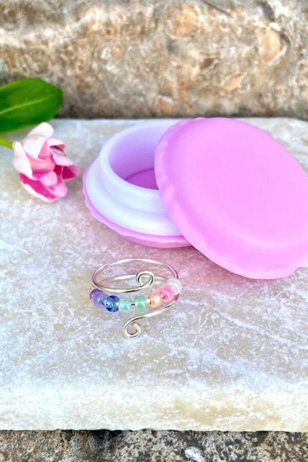 Silver anxiety fidget rings with pastel rainbow beads and macaron container