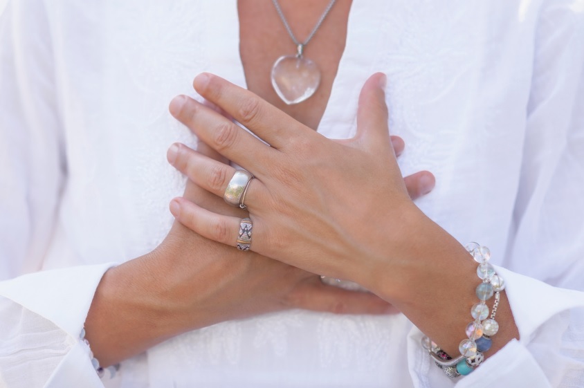 women wearing a heart crystal necklace guarding her heart with hands covering heart